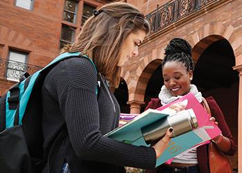 two female students looking at notes outdoors