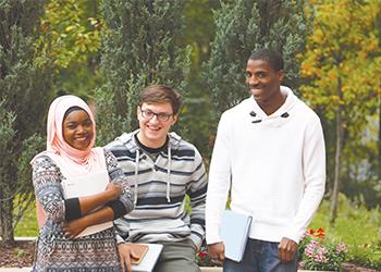 three students with books smiling outside