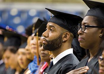 male graduate in cap and gown looking focused