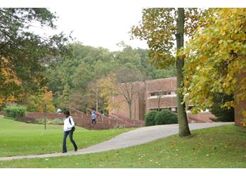 student walking by a building with autumn foliage