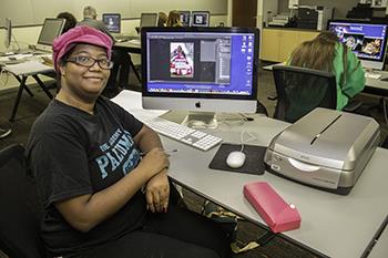 student smiling at a computer desk