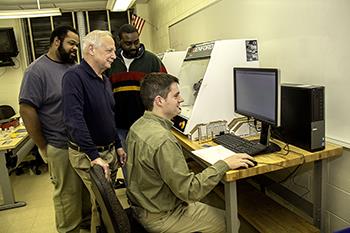 three people observing computer work