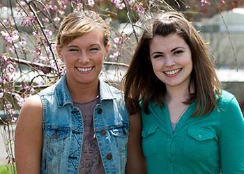 two students smiling near blossoms