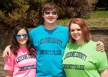 three students wearing college t-shirts