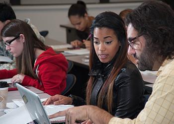 teacher assisting student at computer