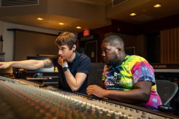 two people at a mixing console in a recording studio