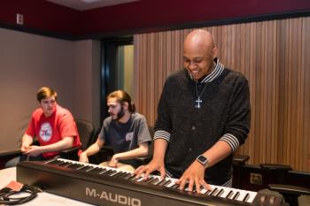 instructor playing piano in a music studio