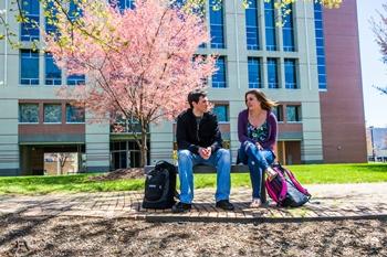 two students sitting outdoors on campus