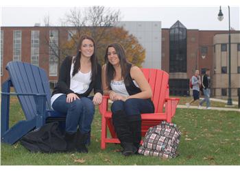 two students sitting on red chairs outdoors