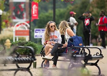 two students sitting on bench talking