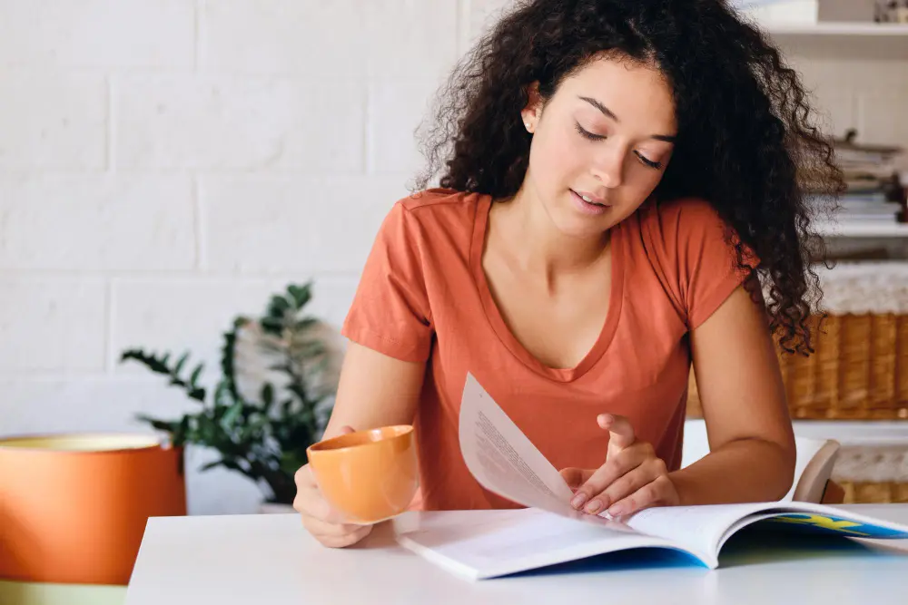 female reading at desk wearing orange shirt