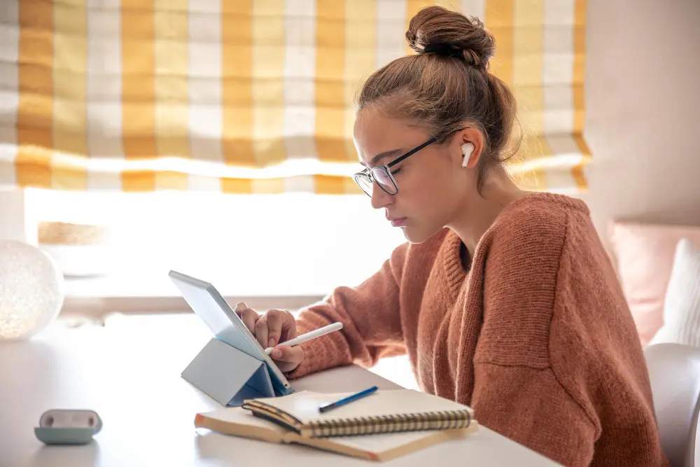 female student studying at table on tablet
