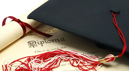graduation cap and deploma on table