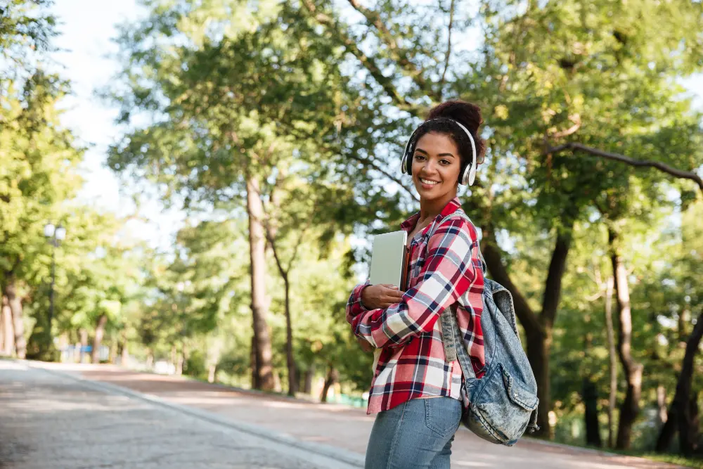 female walking on campus listening to music and smiling