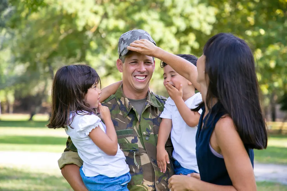 man in military attire being greeted by family