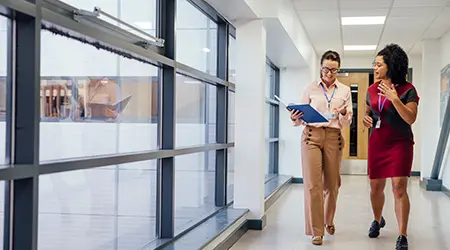 two people walking down school hallway